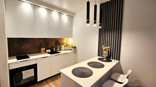 een keuken met witte kasten en een tafel met een stoel bij Apartament Amber Suite in Międzyzdroje
