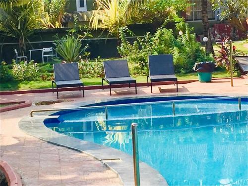 two chairs sitting next to a swimming pool at Sana Villa & Resort Anjuna Beach Goa in Anjuna