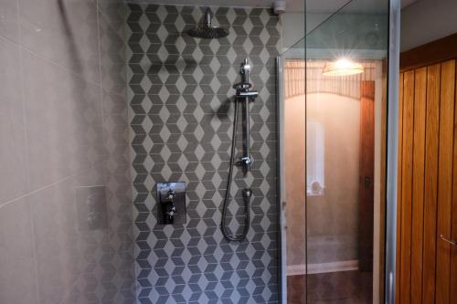 a bathroom with a shower with a tile wall at The Granary Cottages 
