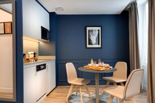Una cocina y un comedor con mesa y sillas. en Serotel Suites Opera, en París
