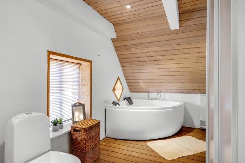 a bathroom with a white tub and a wooden ceiling at Stort byhus i centrum af Skagen in Skagen