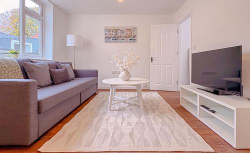 a living room with a couch and a tv and a table at 58b Thorpe Road - City Centre in Norwich