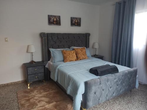 een bed met een blauw dekbed en een koffer erop bij Bright & Spacious En-suite Room - Santo Domingo Este in Cancino