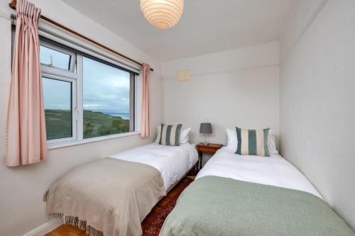 two beds in a room with a window at Finest Retreats - The Breakers in Poughill