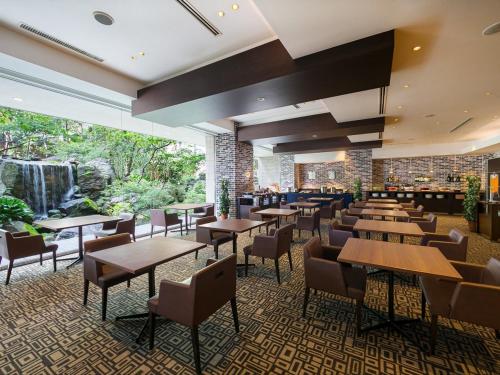 a restaurant with tables and chairs and a waterfall at Hotel New Nagasaki in Nagasaki