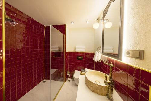 een badkamer met rode tegels, een wastafel en een douche bij Zerzembe Boutique Hotel in Sanlıurfa