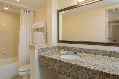 a bathroom with a sink and a mirror and a toilet at Shutters on the Banks in Kill Devil Hills