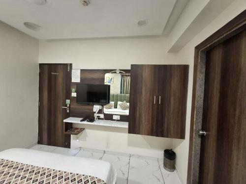 une chambre avec un lit et une télévision sur un mur dans l'établissement Hotel Asiana, à Sardar Vallabhbhai Patel International