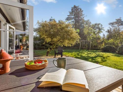 an open book on a table with a cup and a basket of fruit at Holiday Home Tameran - 1km from the sea by Interhome in Gedesby