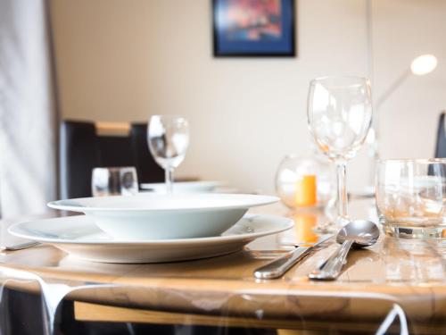 a wooden table with plates and wine glasses on it at Apartment Morgensonne B1105 by Interhome in Rhens