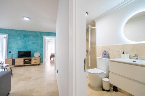TV y baño con aseo y lavabo. en Apartamentos Maresía by Infinity Summer, en Las Palmas de Gran Canaria