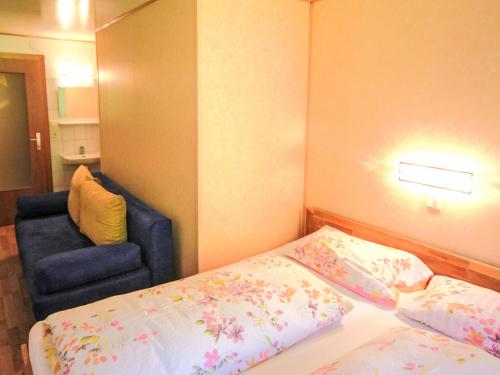 a small bedroom with a bed and a blue chair at Apartment Apartment Kriasi by Interhome in Gortipohl