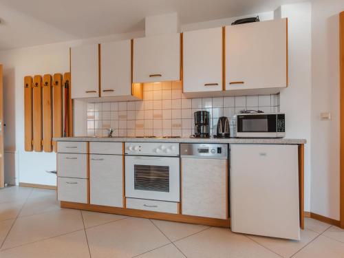 a kitchen with white appliances and white cabinets at Apartment Voithofer-6 by Interhome in Königsleiten