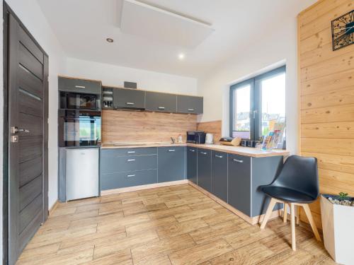 a kitchen with blue cabinets and a black chair at Chalet Osada Orlica by Interhome in Lasowka