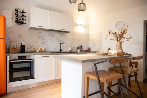 a kitchen with white cabinets and a counter with stools at Ca' Dij Noni in Strona