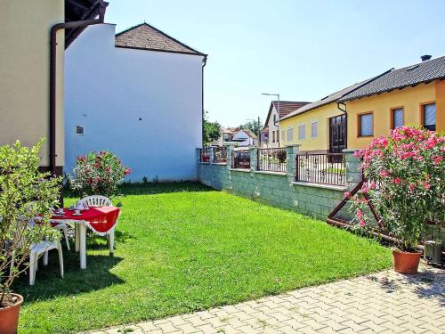 a yard with a red table and chairs and flowers at Holiday Home Pannonia by Interhome in Unterfrauenhaid