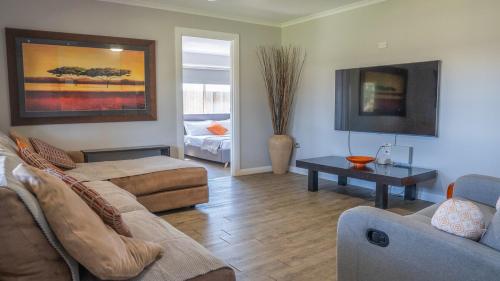 una sala de estar con un sofá y una mesa en Stays with Ripley 3 min to hospital and beach Pet friendly, en Urraween
