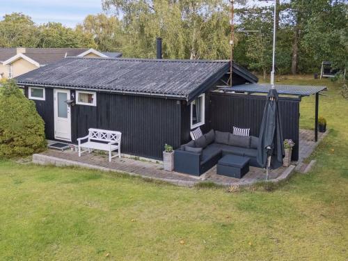 a black shed with a couch and a bench at Holiday Home Baarde - 1-2km from the sea by Interhome in Vejby