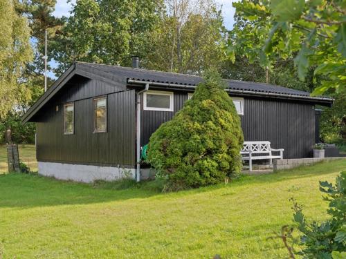 a black cottage with a bench in front of it at Holiday Home Baarde - 1-2km from the sea by Interhome in Vejby