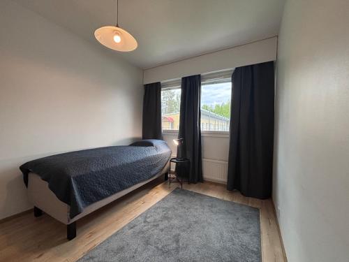ein Schlafzimmer mit einem Bett und einem großen Fenster in der Unterkunft Kotimaailma - Cozy and spacious apartment in Seinäjoki