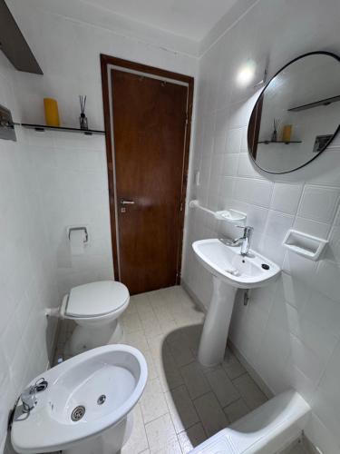 a white bathroom with a toilet and a sink at Torrejon 301 in Villa Gesell