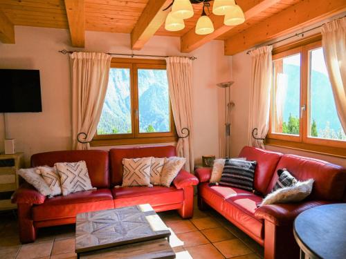 una sala de estar con sofás de cuero rojo y ventanas en Chalet Ecureuil noir by Interhome, en Ovronnaz