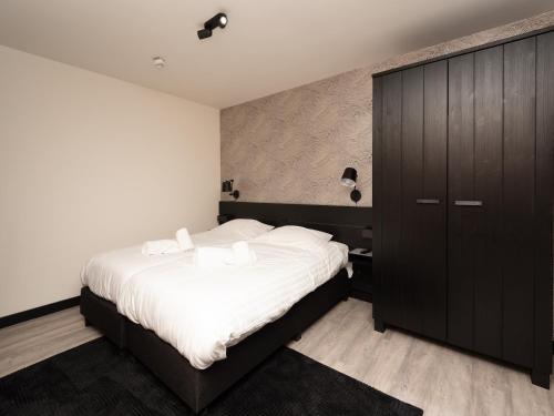a bedroom with a large bed and a black cabinet at Luxury apartment in Renesse with infrared sauna in Renesse