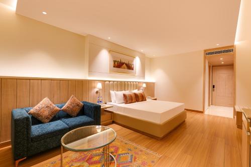 a hotel room with a bed and a blue couch at Lemon Tree Hotel, Motihari in Motīhāri