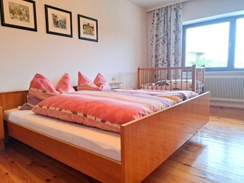 a bedroom with a wooden bed with pink pillows at Holiday Home Lindnerhof by Interhome in Helpfau-Uttendorf