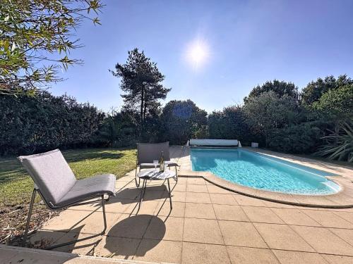 a swimming pool with two chairs and a table next to it at Holiday Home Ma Petite Mer by Interhome in Le Clion-sur-Mer