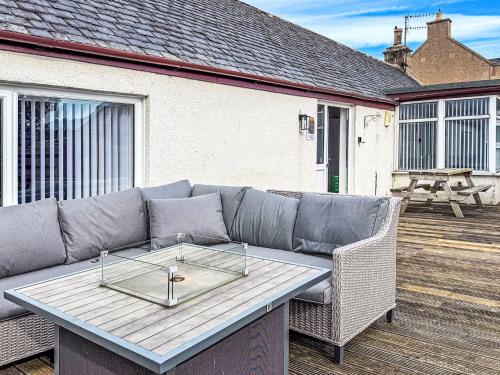 a couch on a deck with a table at Holiday Home Gordonstoun Cottage by Interhome in Duffus