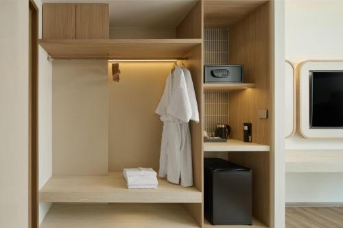 a room with a closet with a robe and a tv at Phetara Hotel Mahachai by PCL in Samut Sakhon