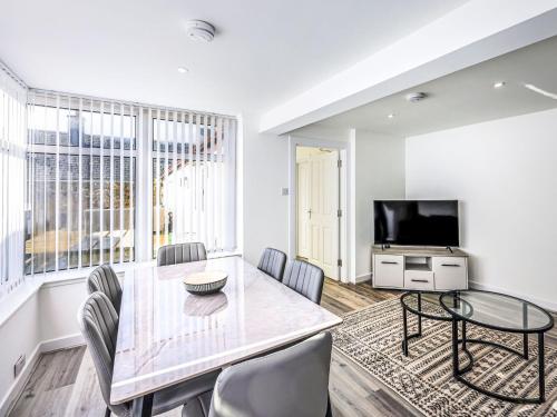 a dining room with a table and chairs and a tv at Holiday Home Gordonstoun Cottage by Interhome in Duffus