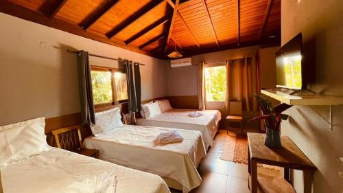 a room with two beds and two windows at Chale Encanto do Rio in Porto Seguro