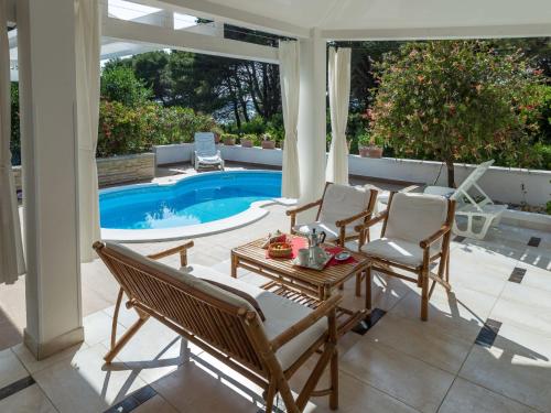 a patio with chairs and a table and a pool at Holiday Home Maya by Interhome in Brgulje