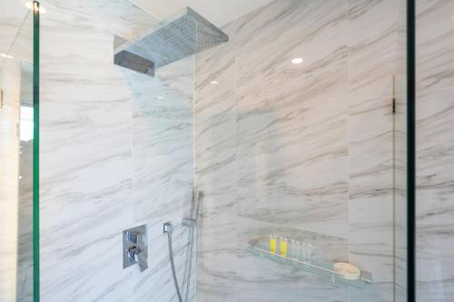 a shower with white marble walls and a glass door at Elegant 2BR Oceanview Condo Oceana C73 - 5 min walk Kamala Beach in Kamala Beach