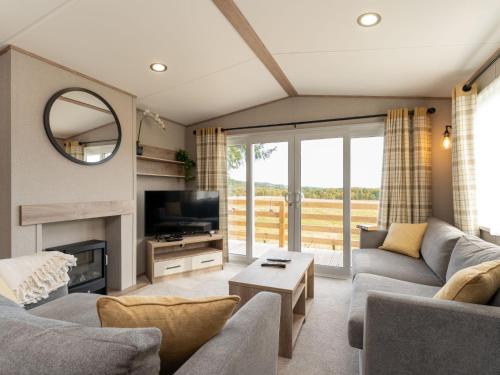 a living room with a couch and a tv at Chalet Lodge 15 by Interhome in Boat of Garten