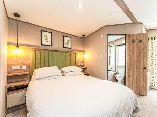 a bedroom with a large white bed and a bathroom at Chalet Lodge 15 by Interhome in Boat of Garten
