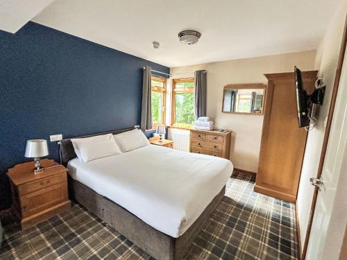 a bedroom with a white bed and a blue wall at Studio Room 26 by Interhome in Nairn