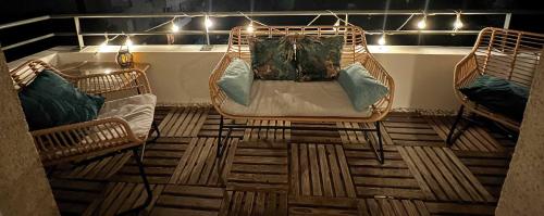 a porch with two chairs and a bed with pillows at Charme et Douceur By UTA HOUSE in Saint-Denis