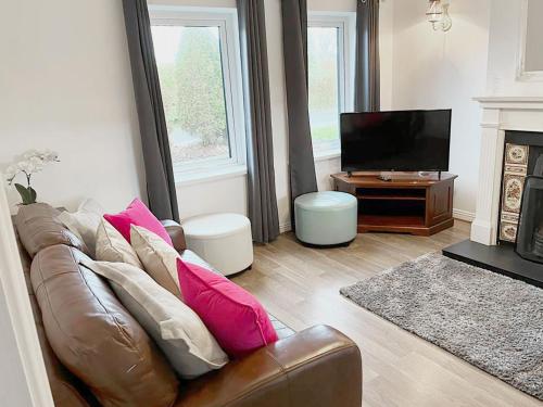 a living room with a brown leather couch and a television at Holiday Home Burren Seaside Lodge by Interhome in Ballyvaughan