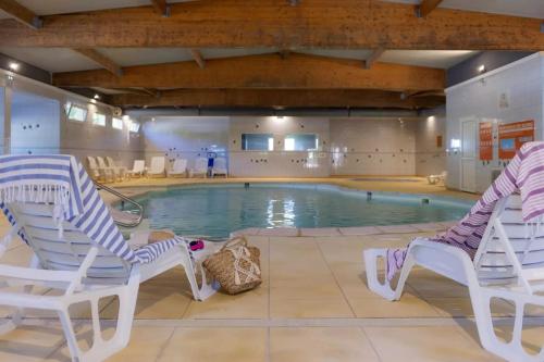 una piscina con 2 sillas y una piscina en Mobilhome au Camping le Ried, en Boofzheim