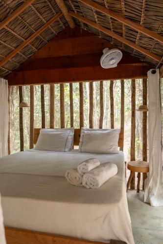 a bedroom with a bed with towels on it at Na Floresta Glamping in Pôrto de Pedras