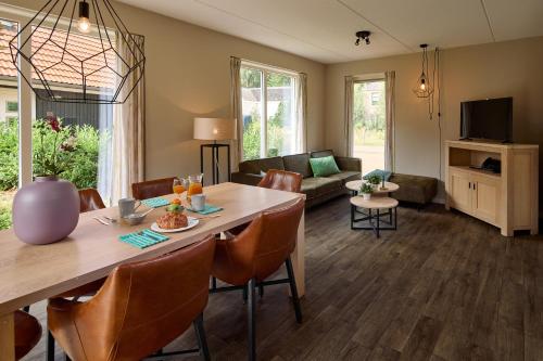 a dining room and living room with a table and chairs at Villapark Ehzerburg in Almen