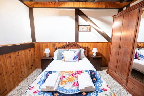 a bedroom with a bed with wooden walls and wooden furniture at Refugio con encanto en la Gomera con vistas a las montañas in Arure