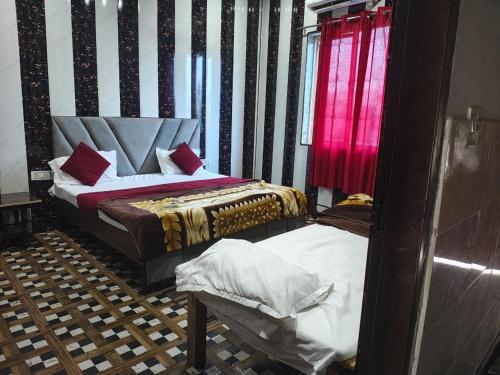 a bedroom with two beds and a red curtain at Priyakant palace in Chhatikara