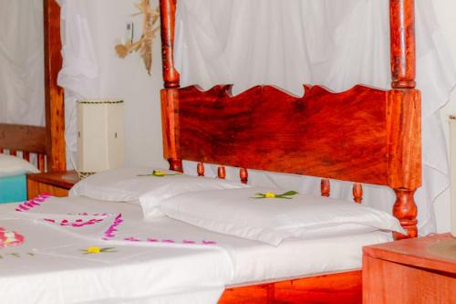 dos camas en una habitación con sábanas blancas y decoración en Mwazhouse, en Watamu