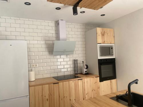 eine Küche mit Holzschränken und einer Mikrowelle in der Unterkunft DOMUS AGER - Casa rural en Mahora in Mahora