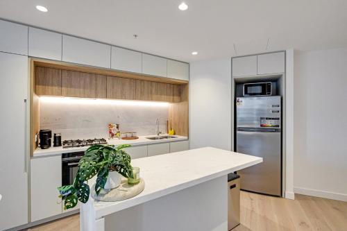 a kitchen with white cabinets and a potted plant at CBD Elegant 2BR Apt with Pool, Gym & City Views in Melbourne