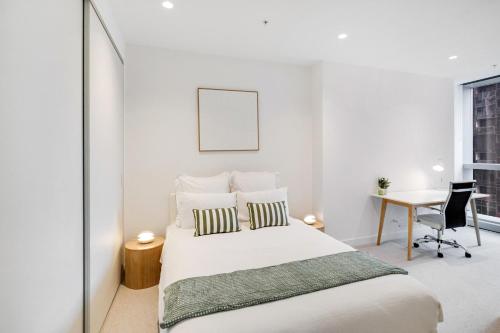 a white bedroom with a bed and a desk at CBD Elegant 2BR Apt with Pool, Gym & City Views in Melbourne